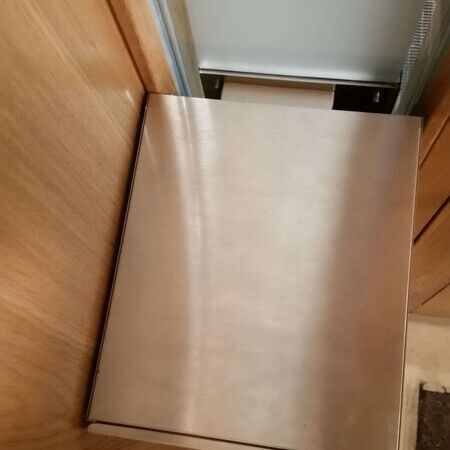 Nahaufnahme eines Edelstahlbriefkastenschlitzes in einer Holz-Eingangstür