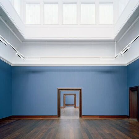 Blauer Raum in der Kunsthalle Hamburg mit einem Holzfußboden, zwei Türen und einem bemerkenswerten Effekt von aufeinanderfolgenden Türen, die in den Hintergrund führen, unter einem weißen Glasdach, das das natürliche Licht in den Raum lässt