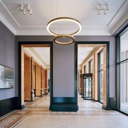 Kunsthalle Hamburg mit modernen Pendelleuchten, einem digitalen Bildschirm an der Wand und einem offenen Durchgang, der zu einem Rotationsportal und großen Fensterflächen führt