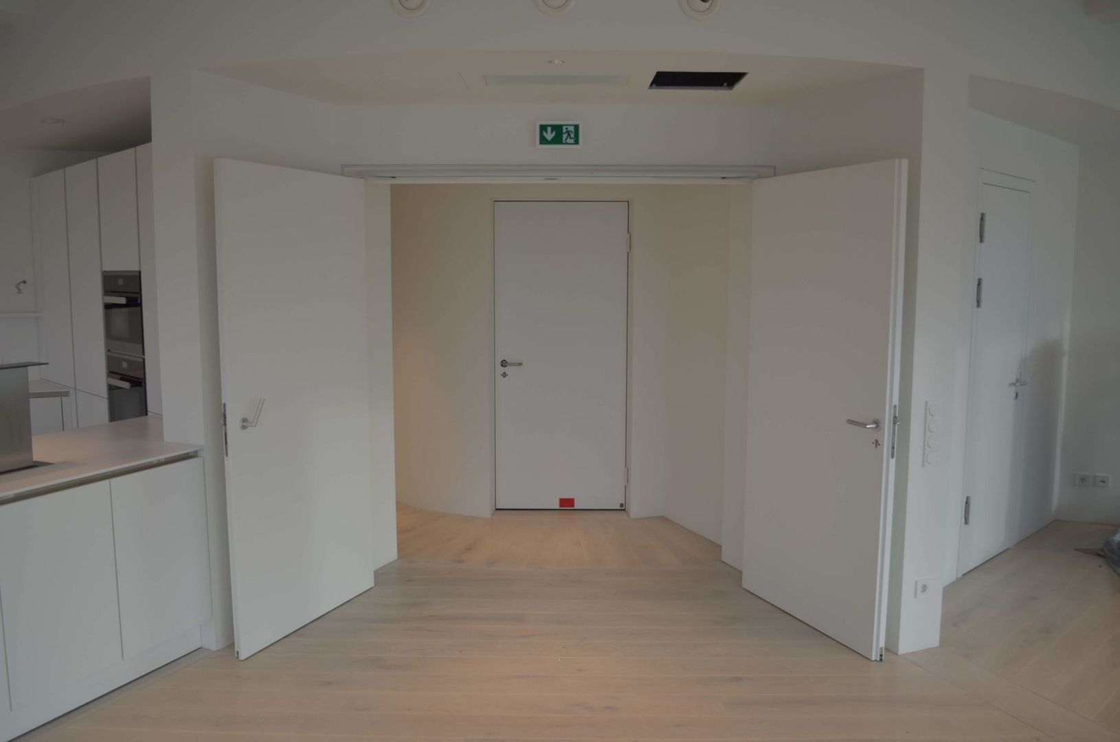 Eingang zu einer modernen Wohnung mit weißen Brandschutztüren und hellem Holzfußboden