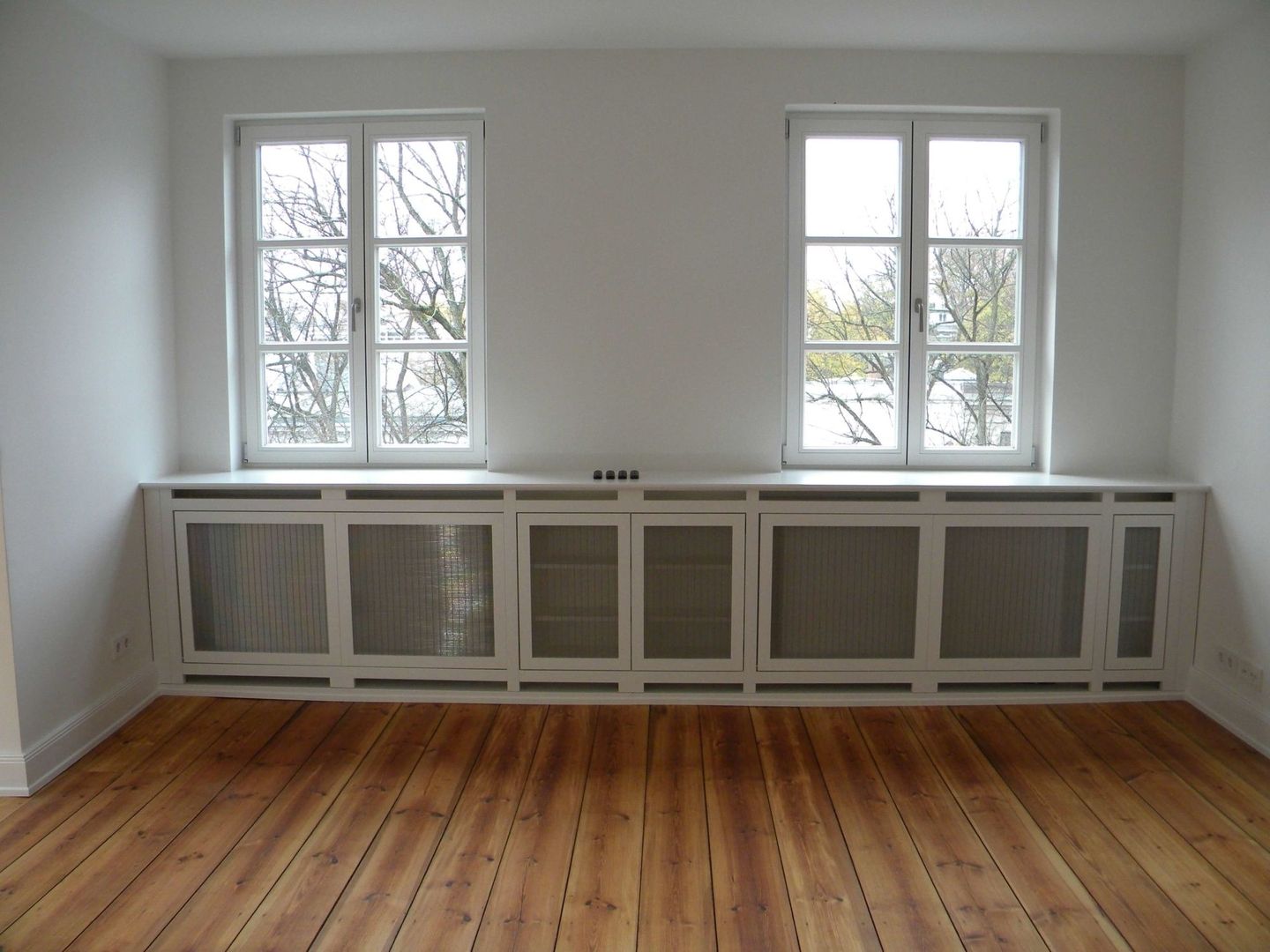 Eine Heizkörperverkleidung in Rahmenbauweise hergestellt unter zwei Fenstern