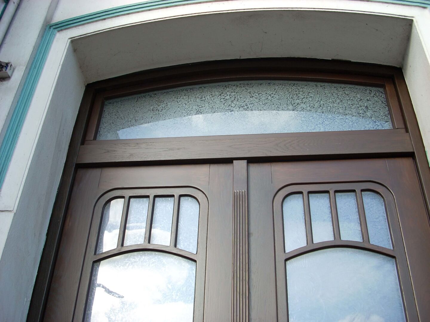 Detailaufnahme eines historischen Eingangstürbogens mit verziertem Glas