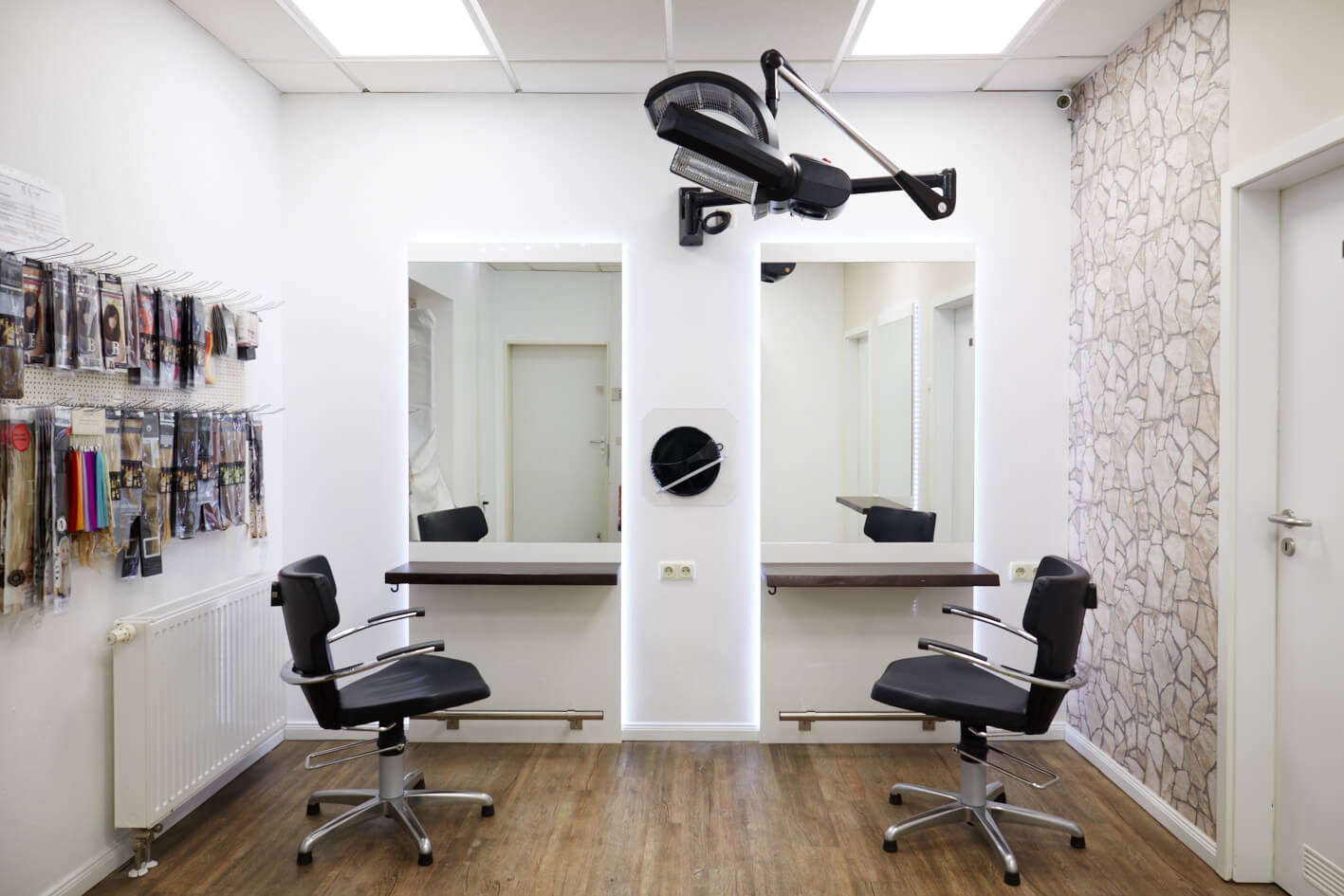 Frisierständer im Friseursalon mit Spiegeln und LED-Beleuchtung. Die weiße Grundplatte wird von LED-Lichtern hinterleuchtet, und die Ablage bietet Platz für einen Föhn
