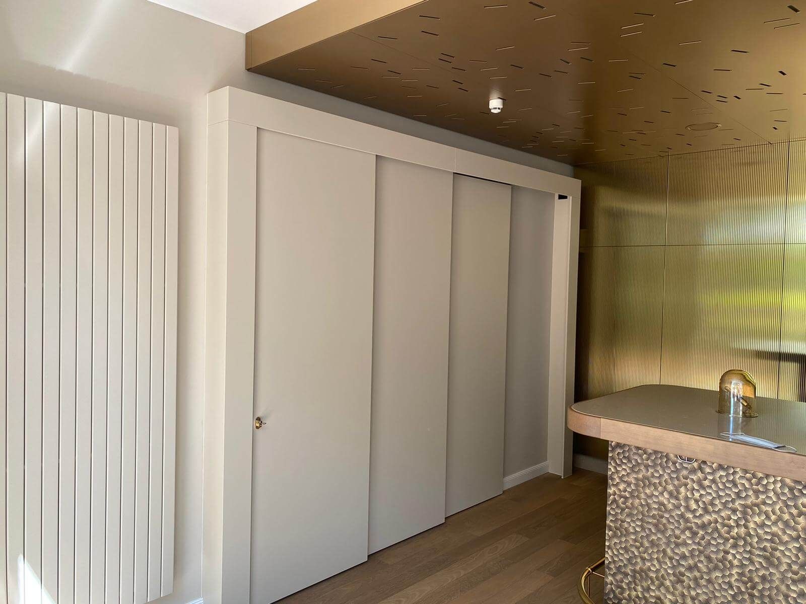 Schiebetür im Eingangsbereich einer Hotelbar, mit einem minimalistischen Design. Die Tür ist in einem neutralen Farbton gehalten, umgeben von modernen Wandverkleidungen und einem dezent gestalteten Bartresen